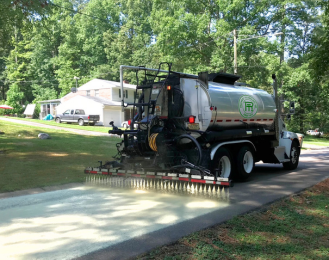 Photo that shows a truck applying asphalt rejuvenator treatment to a road